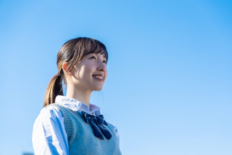 外で遠くを見る制服を着た女子高生