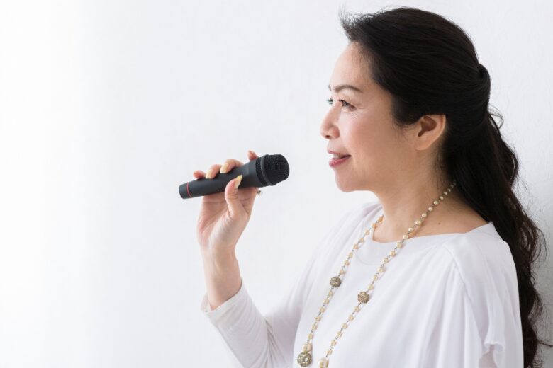 マイクを持って歌うミドル女性