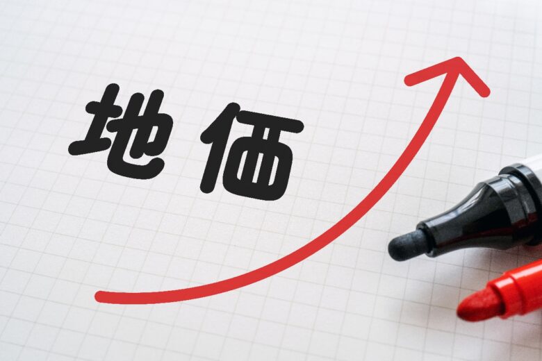 地価と上向きの矢印が書かれたノートとマーカー